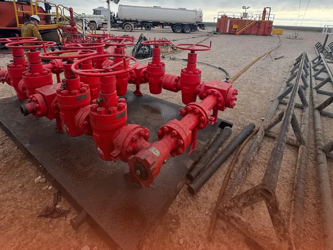 Manifold choke de alta presión de G&M Rental Tools montado en locación, con operario y equipos de la operación al fondo